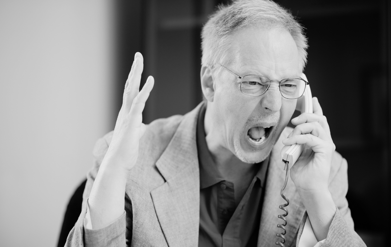 Businessman yelling on the phone, highlighting the challenge of staying professional during tense conversations
